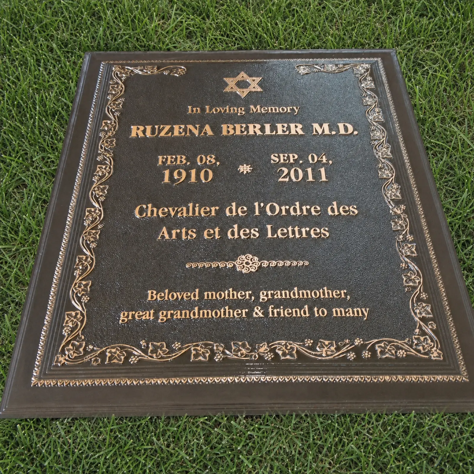 Installed 39 by 30 inch bronze memorial marker with raised lettering and floral border on grass