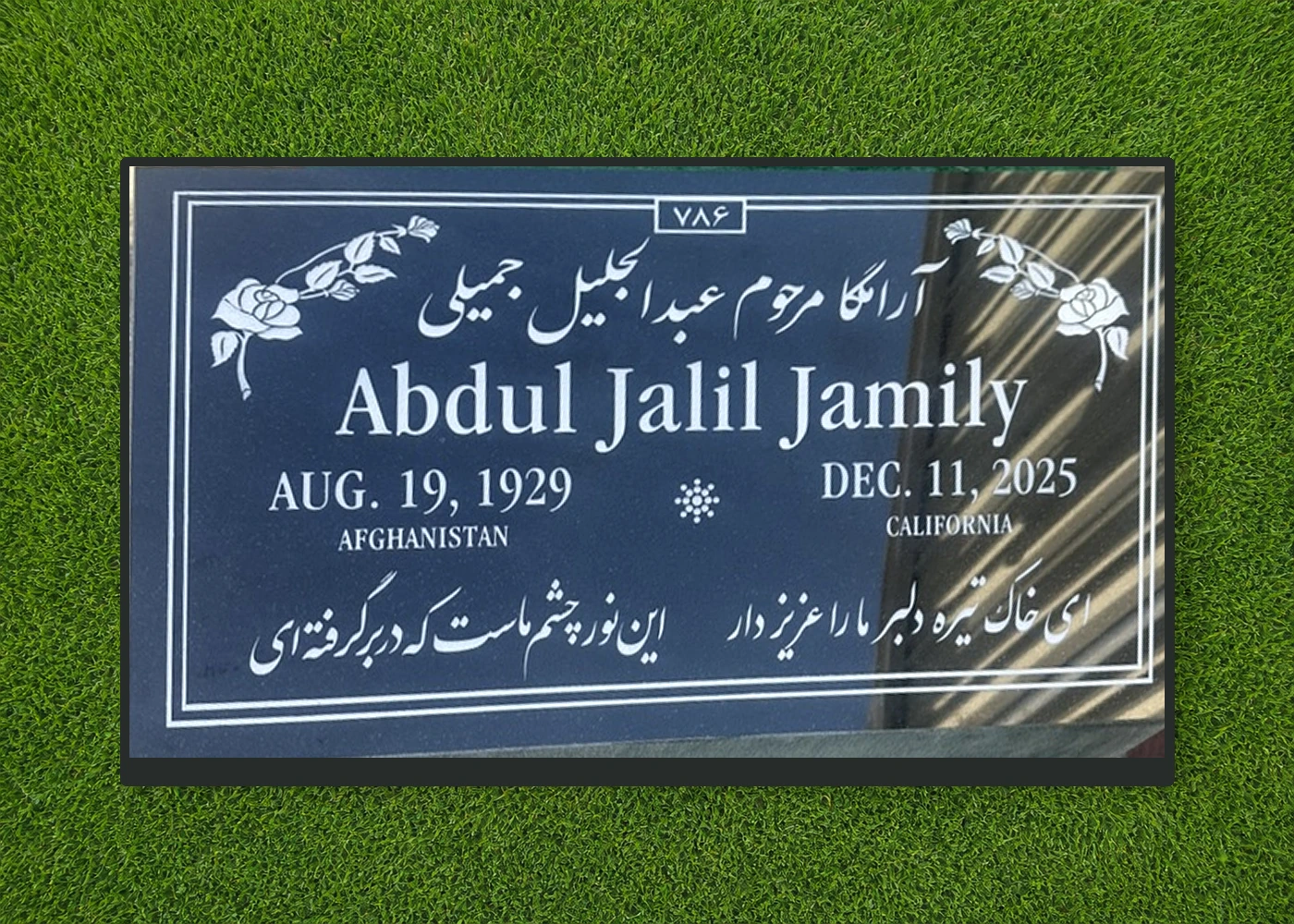 Black granite 28 by 16 inch flat marker with multilingual lettering and rose artwork